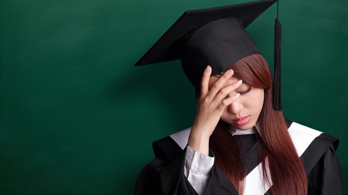Woman in graduation gown looking upset
