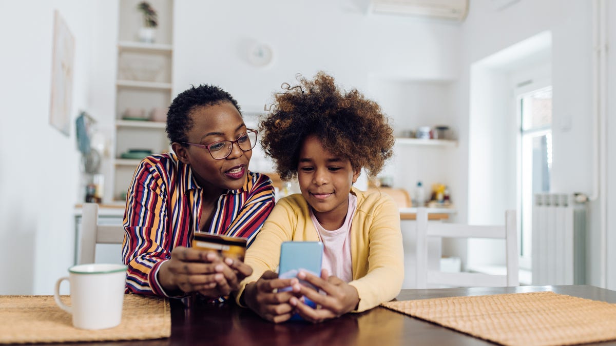 a parent and child looking at smartphones together at a kitchen table