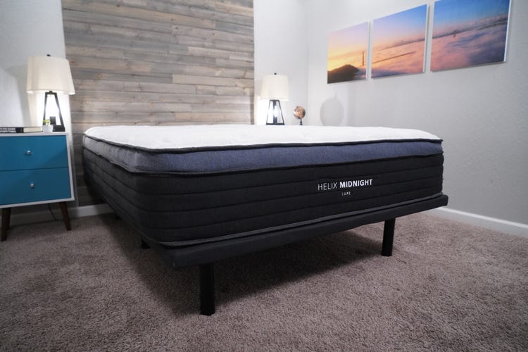 The Helix Midnight Luxe mattress sitting on top of a bed frame in a well-lit room.