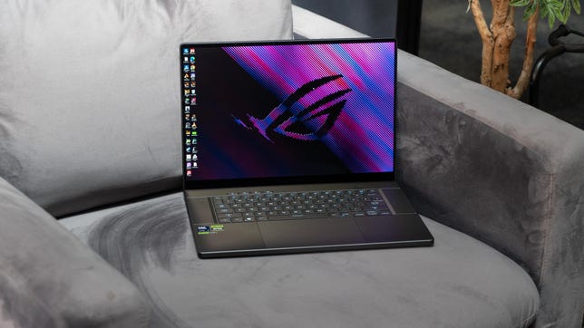 The laptop open and sitting on a gray chair