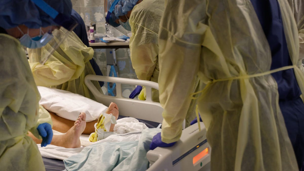 Person in hospital bed as doctors look on.