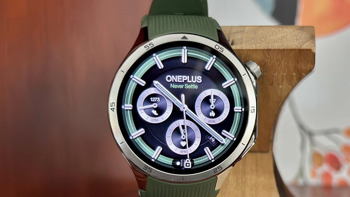 A OnePlus Watch 3 on a wooden stand