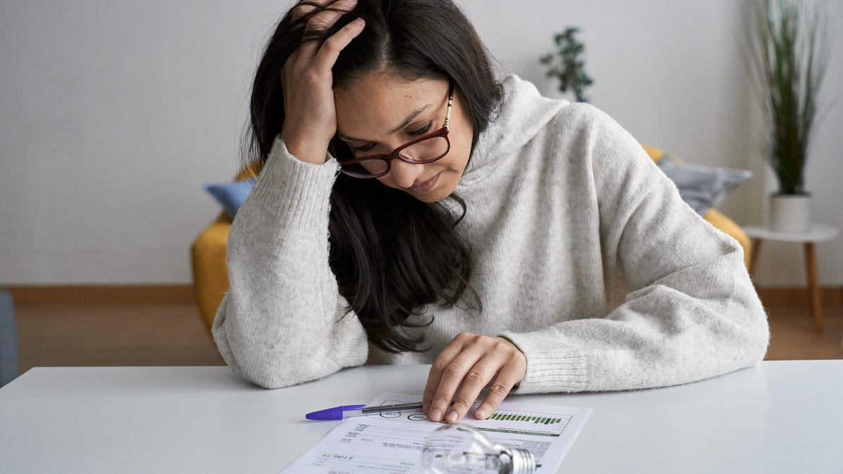 Woman looking worried while checking electricity bill at home