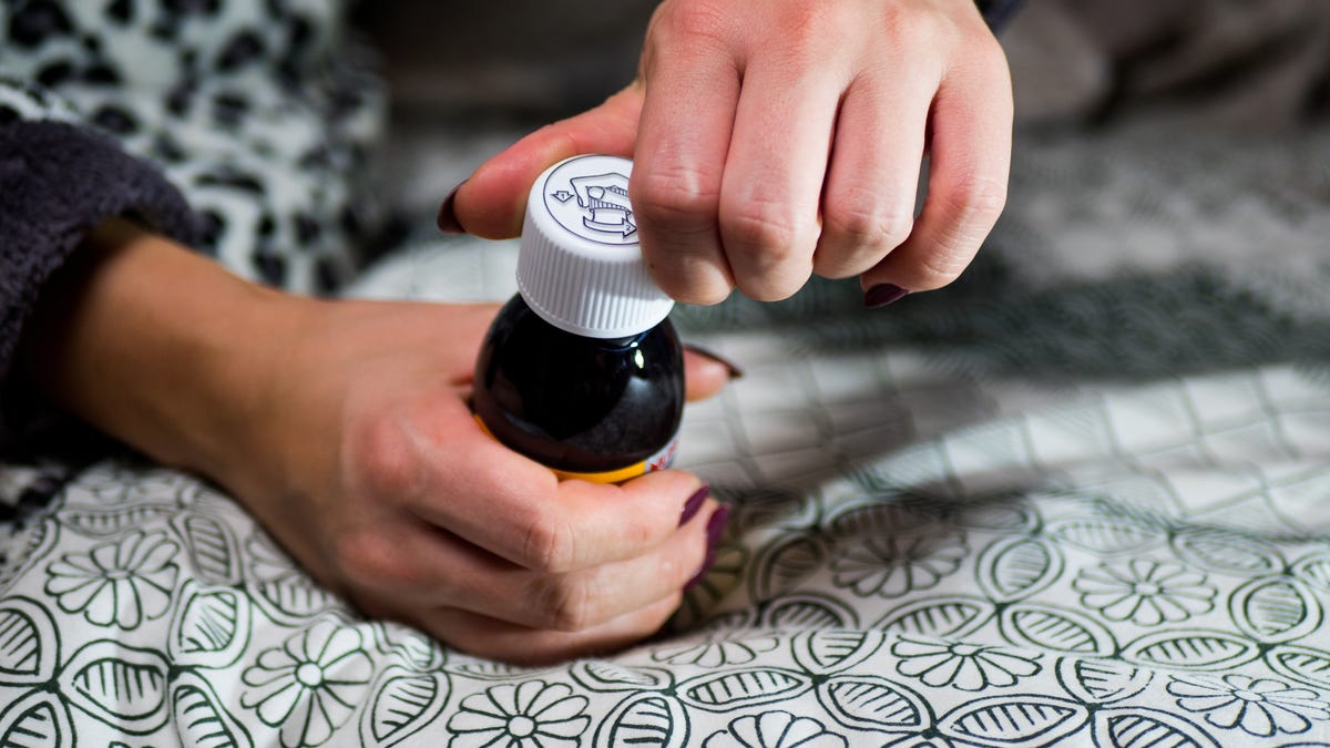 A woman's hands opening a bottle of flu medicine