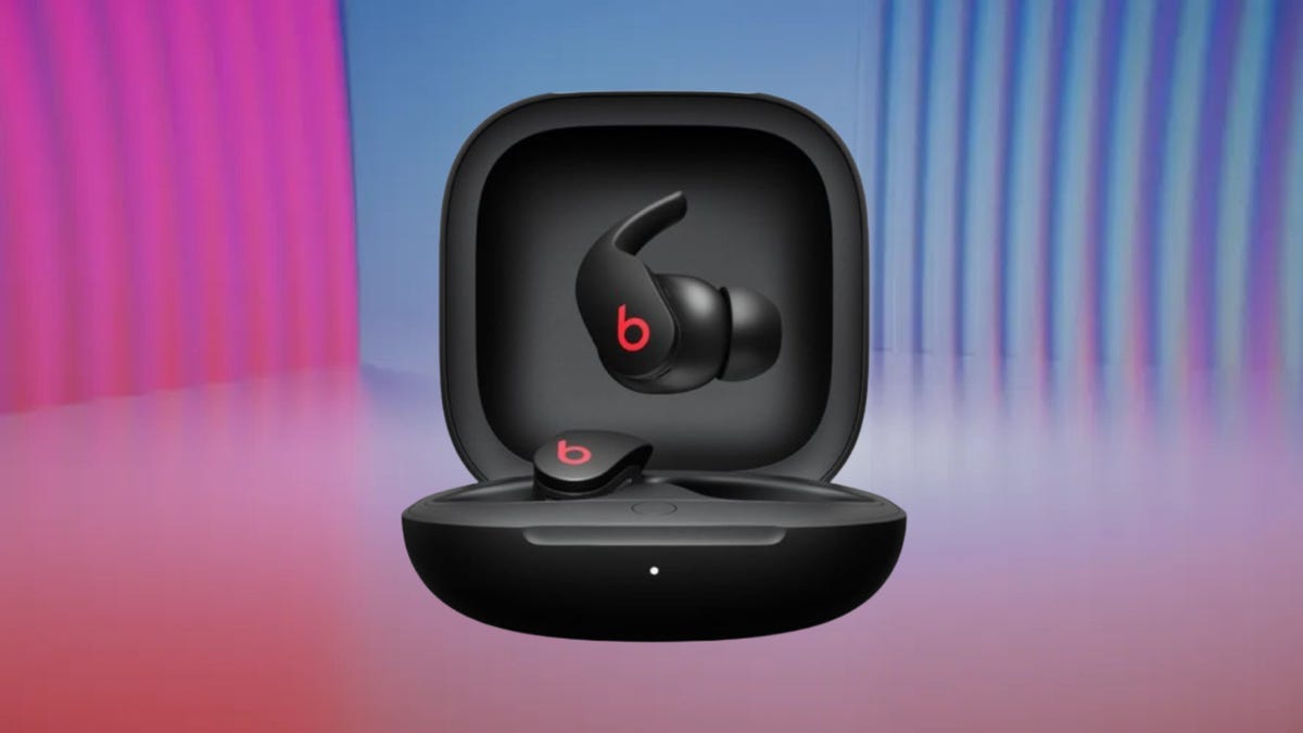 A pair of black Beats Fit Pro with red logo in a black carrying case set against a pink and blue gradient background.
