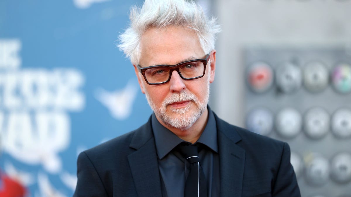 Director James Gunn looks directly at camera with a bright blue Suicide Squad stand in the background