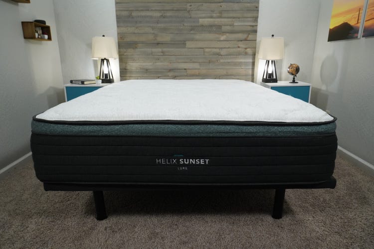 A Helix Sunset Luxe mattress on top of a grey bed frame and in between two nightstands.