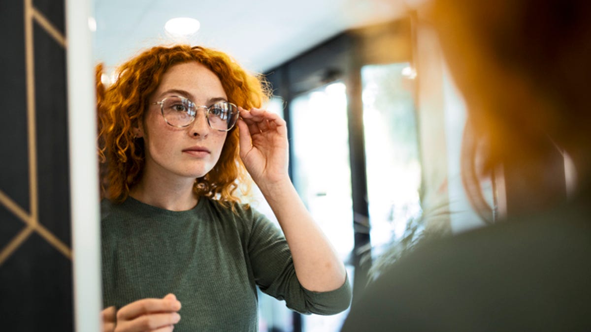 Woman trying on glasses in the mirror.