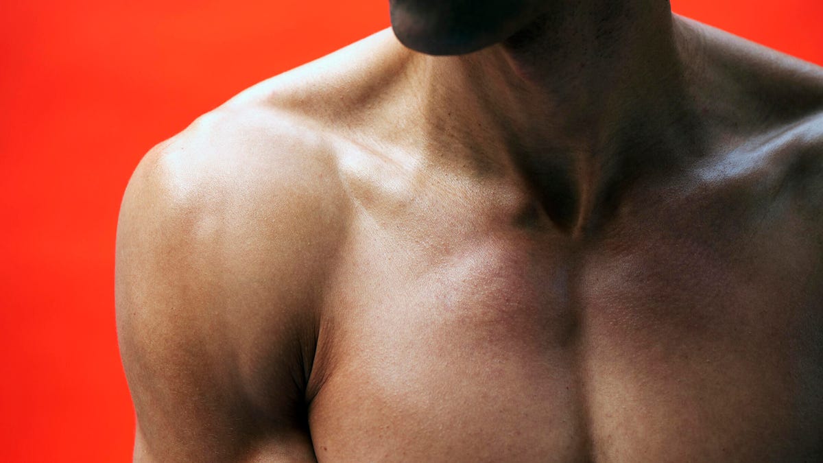 close up of a man's muscular chest on a red background