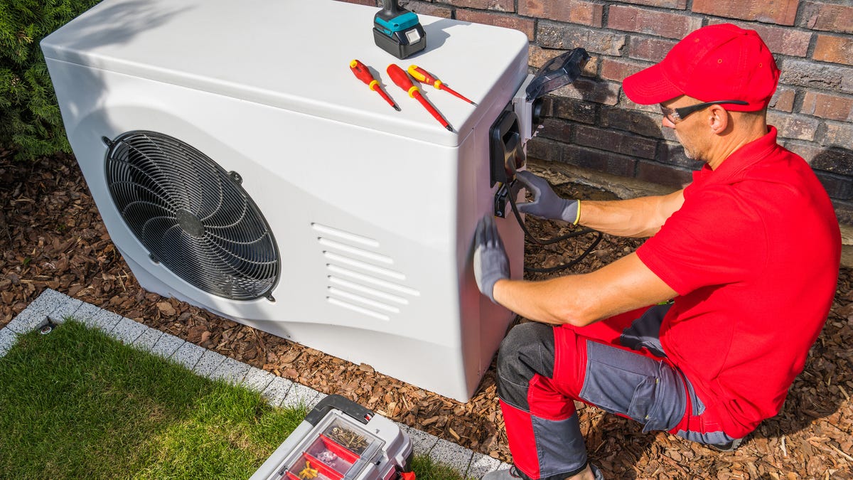 An HVAC installer puts in a heat pump at a home.