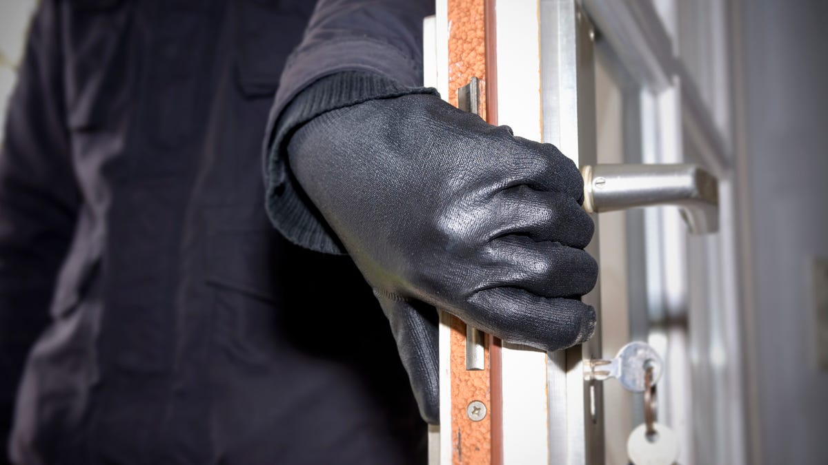 A hand in a black glove opens a windowed door.