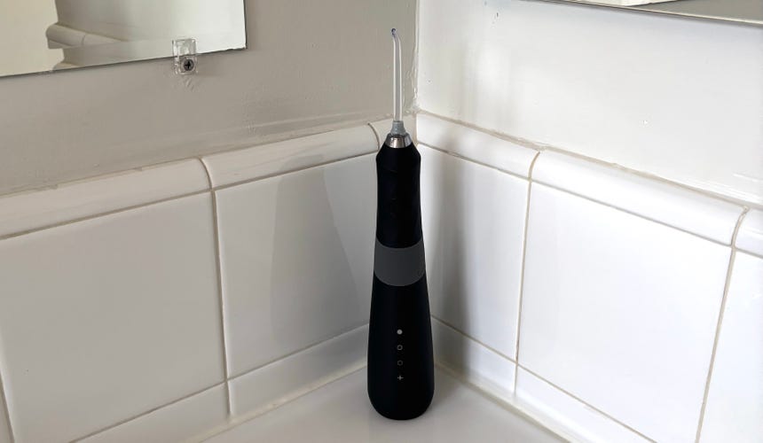 The black Burst Water Flosser on a white bathroom countertop.