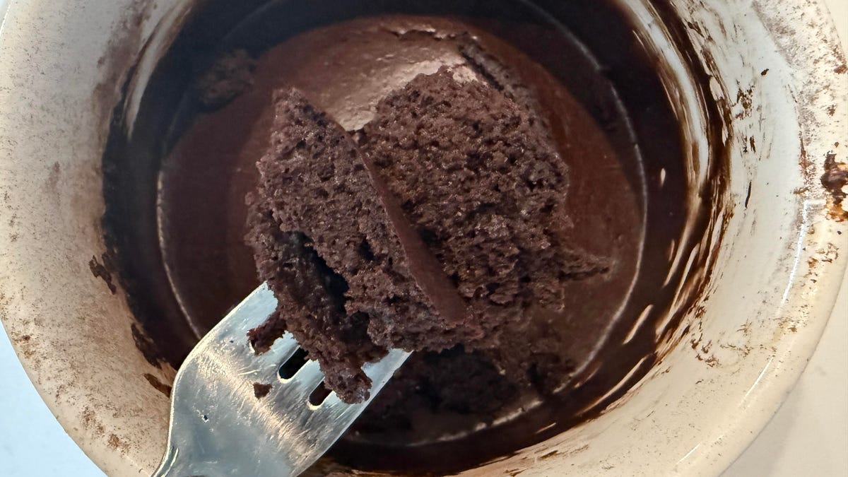 Ariel view of a chocolate mug cake with fork holding a piece of cake.