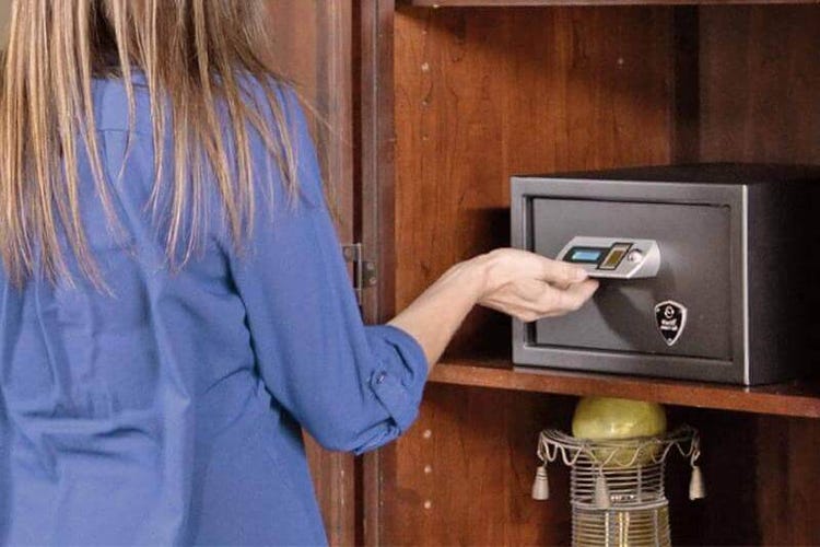 A woman touches a Verifi safe in a wood cabinet.