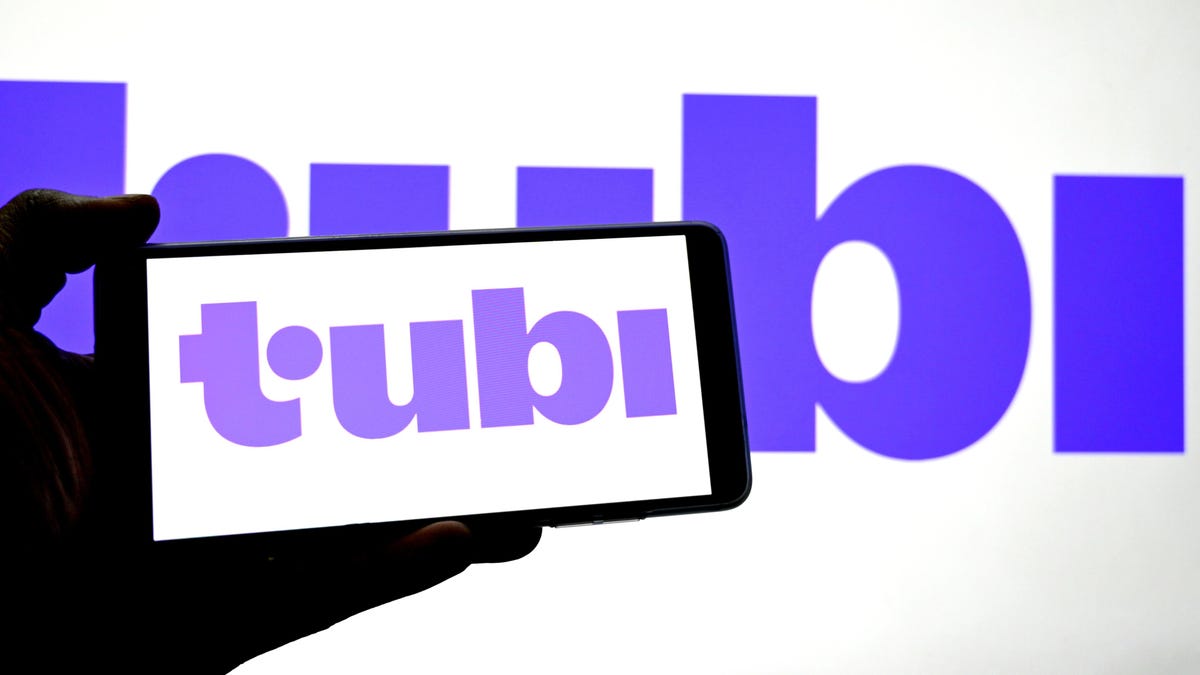 tubi logo on phone with tubi logo on wall in background