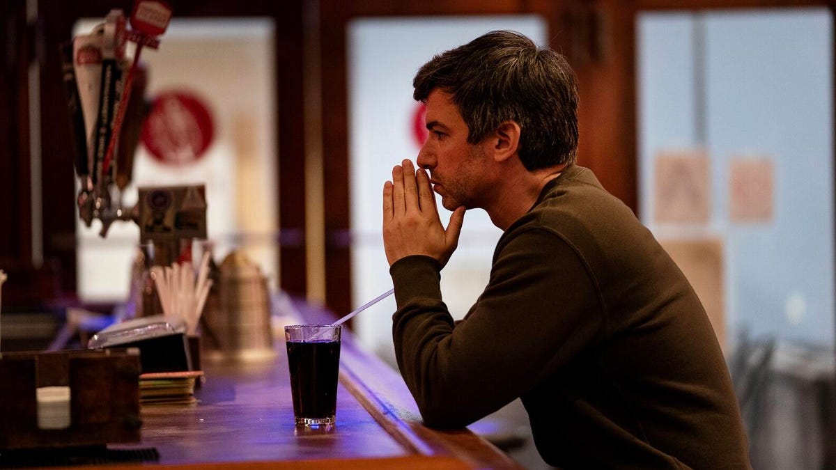 Nathan Fielder messes with a straw while looking deep in thought.