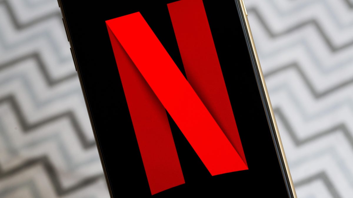 Netflix's logo on a phone against a zigzag backdrop