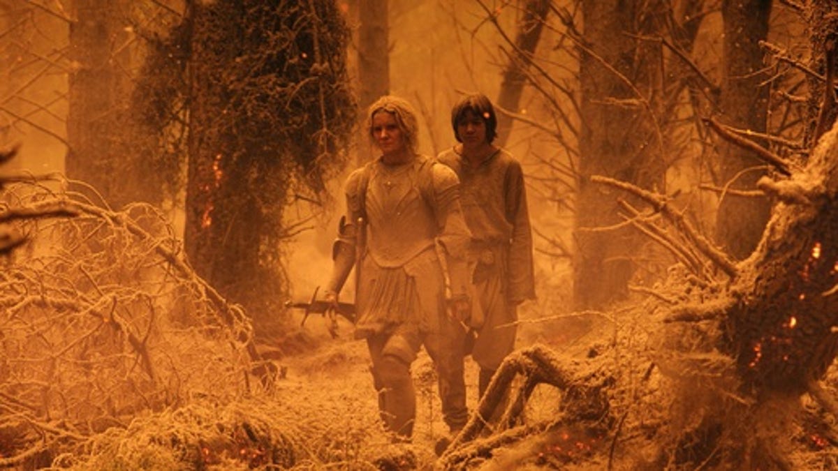 Galadriel and Theo walk through ash-covered woods.