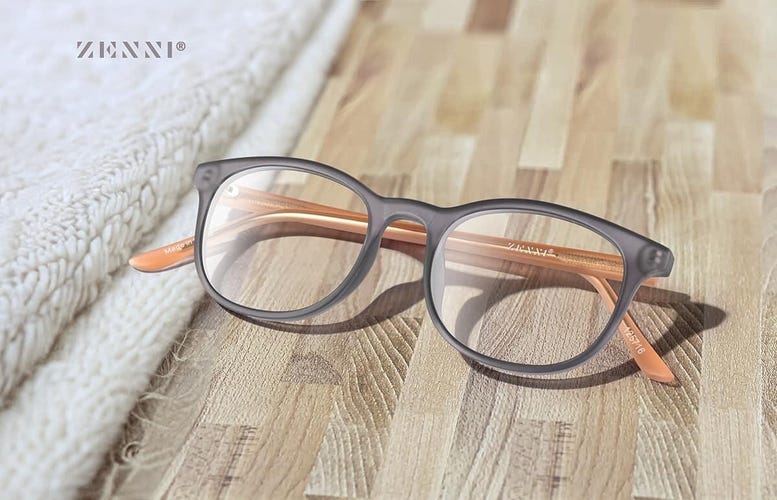 a pair of brown eyeglasses sit folded on a wooden floor next to a folded white carpet
