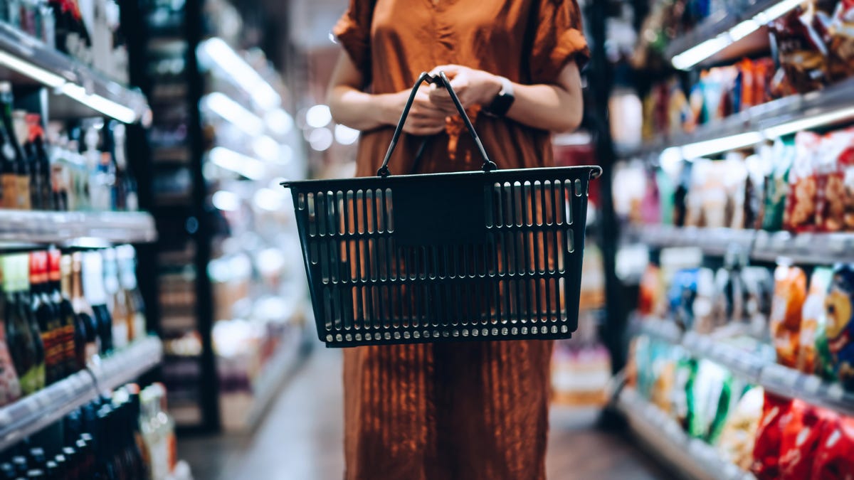 Person in a long brown dress browses a grocery store aisle.