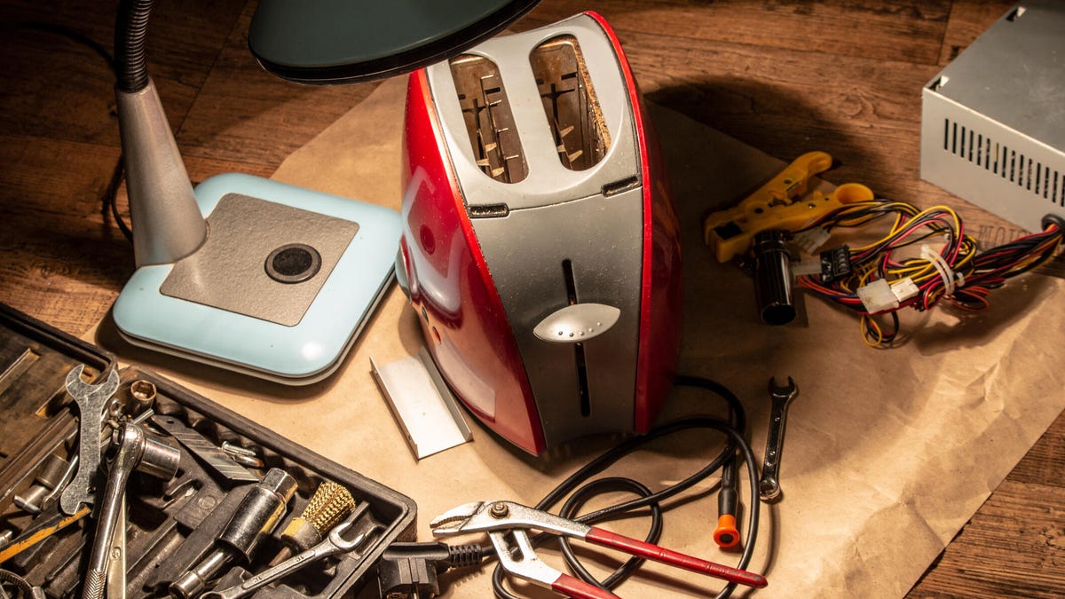 A toaster sits on a table surrounded by tools.