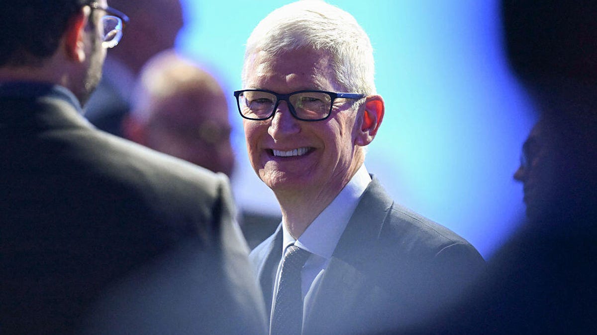 Tim Cook is seen in a photograph over the shoulders of two other people.