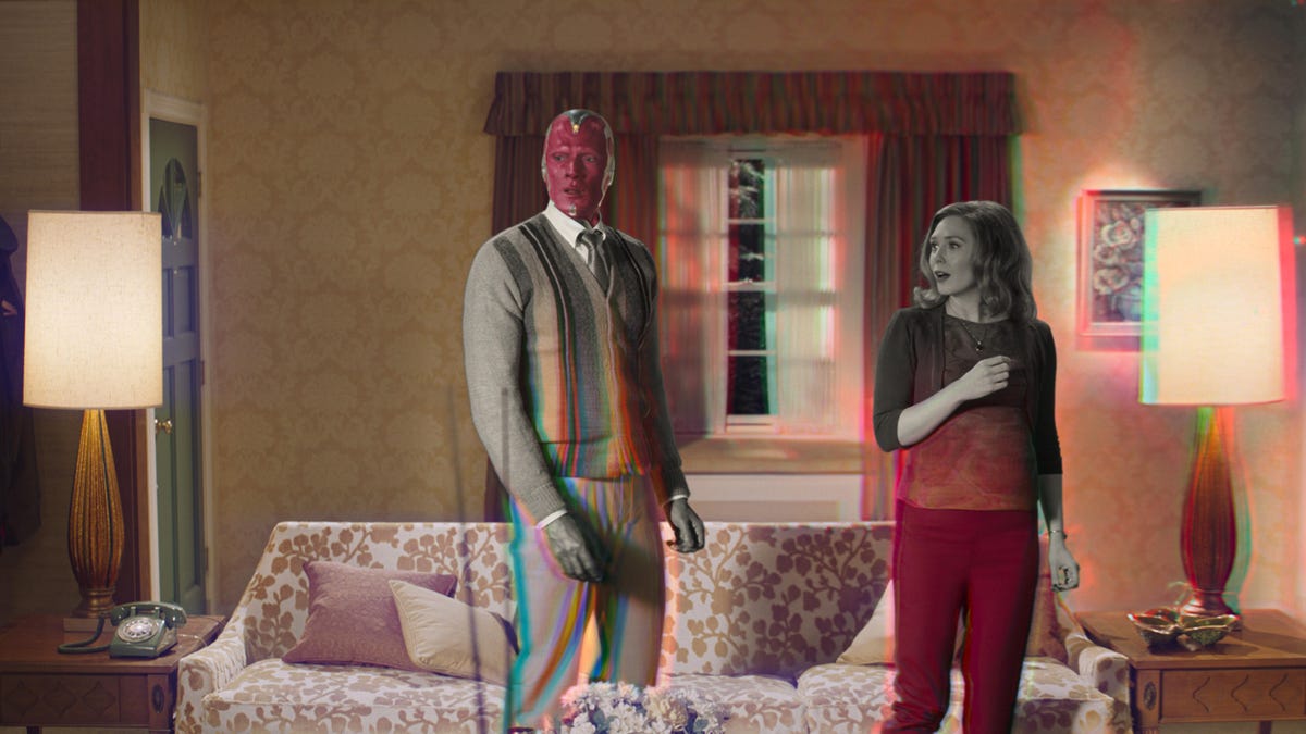 Wanda and Vision stand in a living room, half in black-and-white and half in color