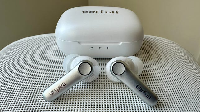 White Earfun Air Pro 4 earbuds and their case rest on top of a white speaker.