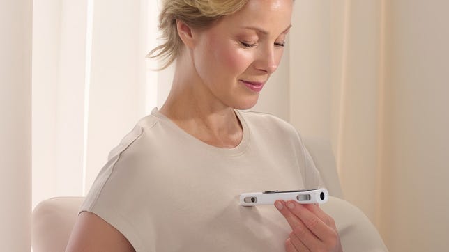 A person holds the BeamO perpendicular up to their chest.