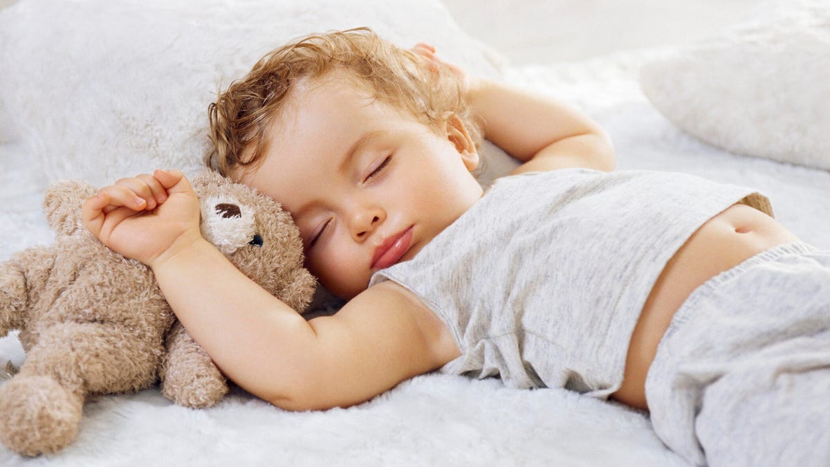 A child sleeping with a bear stuffed animal.