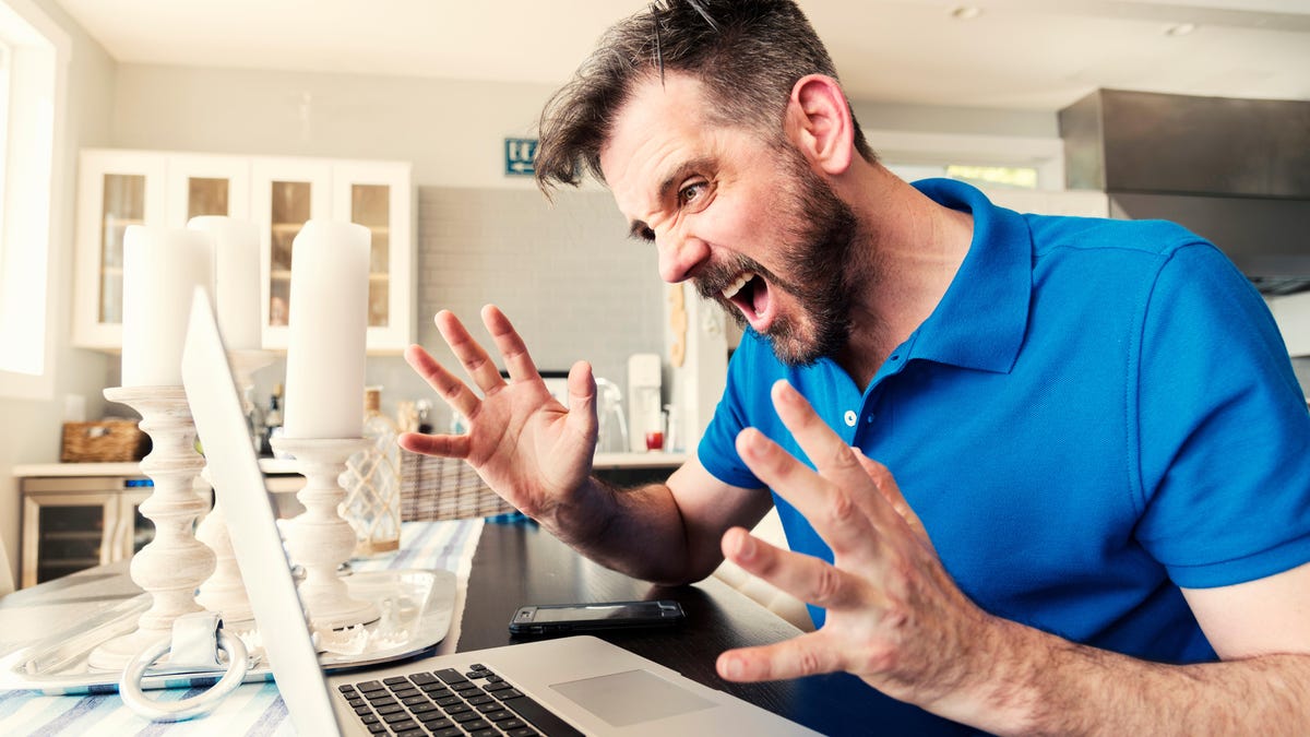 Frustrated Young Man Screaming While Using Laptop