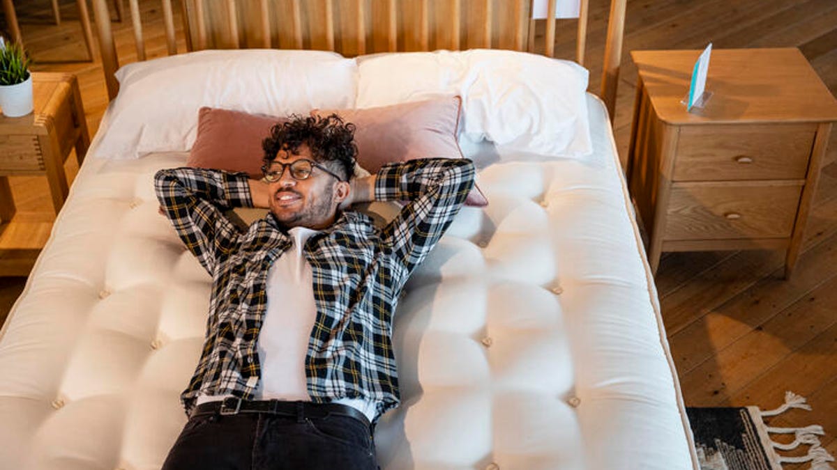Man lying on a queen size bed in a furniture store.