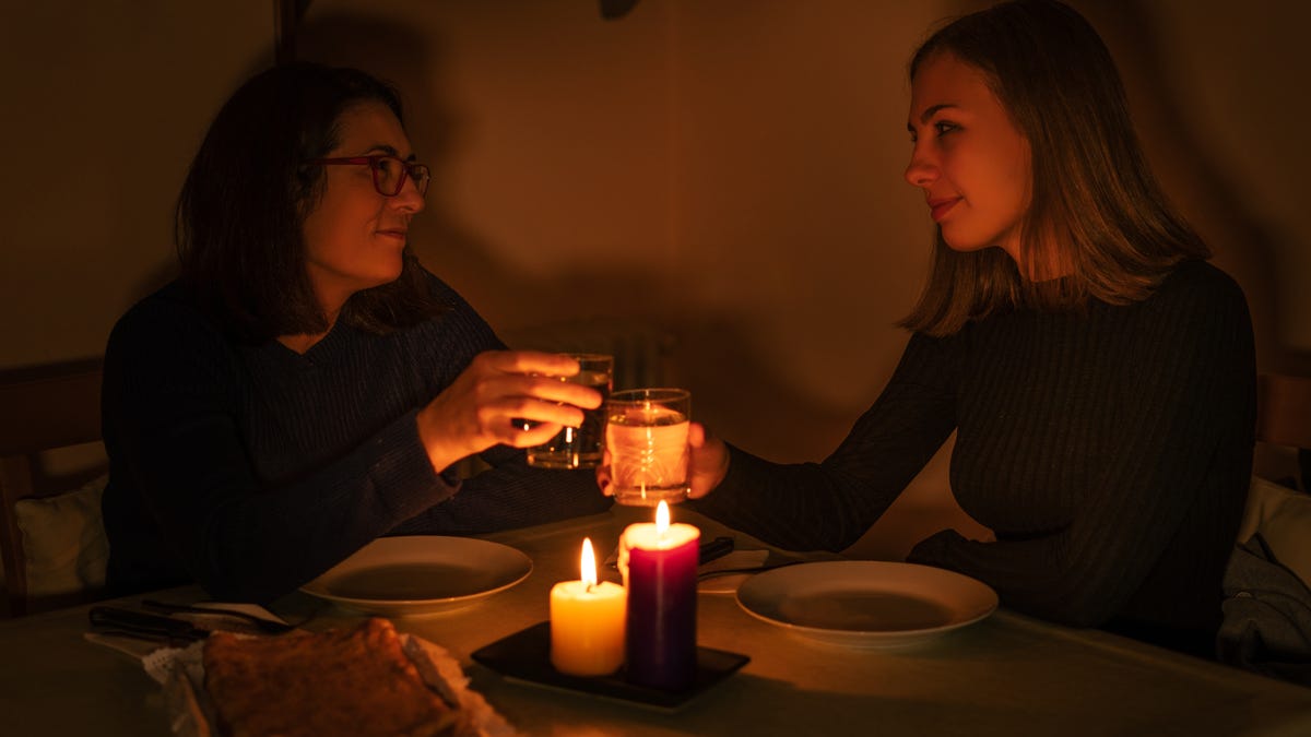 Two women eat by candlelight.