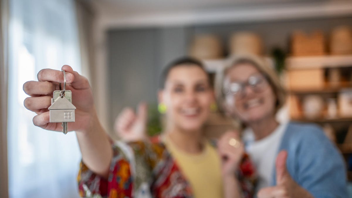 A couple holds up a house key in a room.