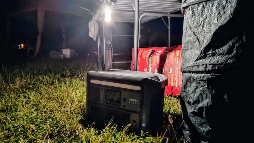 Anker Solix C800 Plus on the ground by a table with one of its camping lights on.