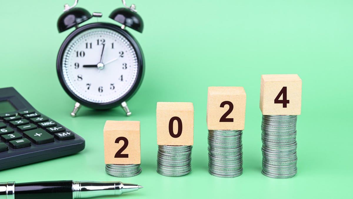 2024 blocks sitting on stack of coins with a calculator and clock in the background