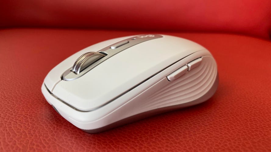A White Logitech MX Anywhere 3 wireless mouse on a red chair.