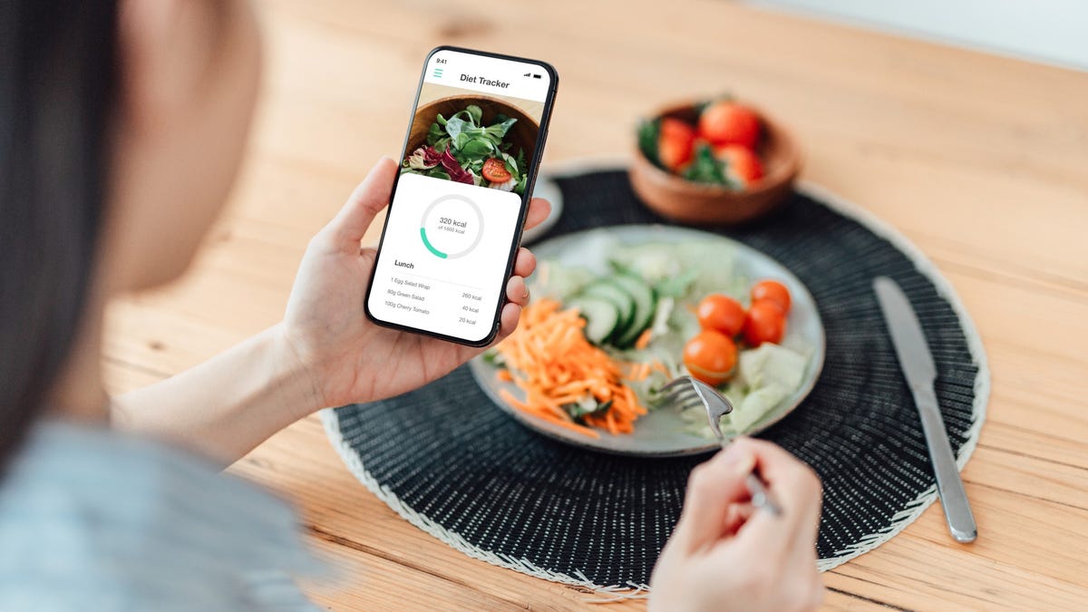 Woman counts calories on a dieting app on her phone