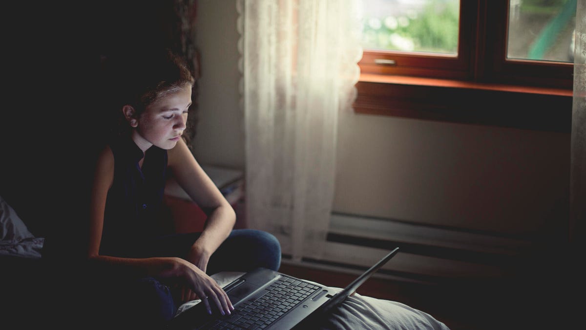 teenage girl on her laptop in a dark room