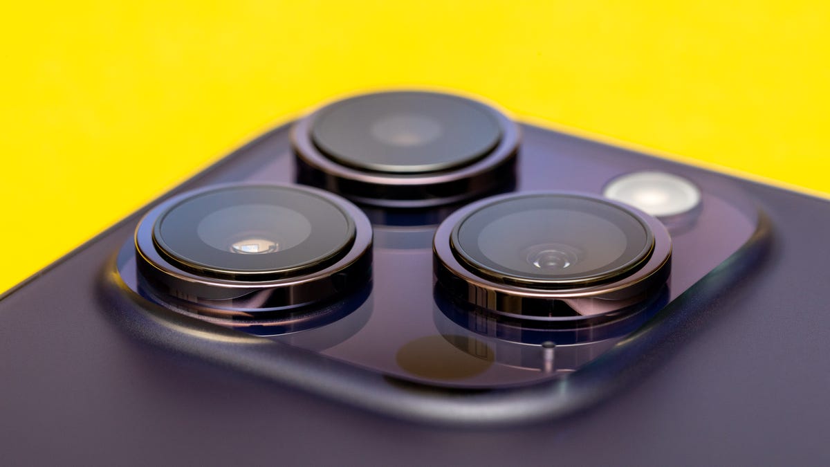 The three rear cameras of a deep purple iPhone 14 Pro point upward