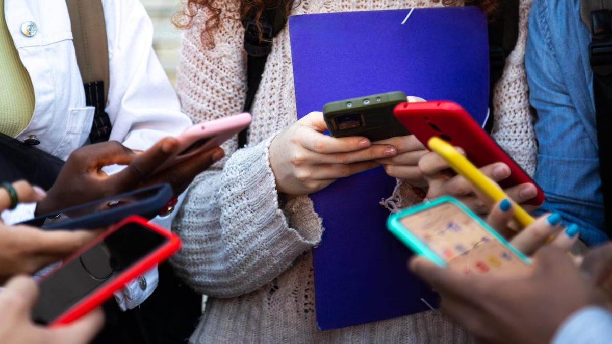 a circle of teens staring at their smartphones