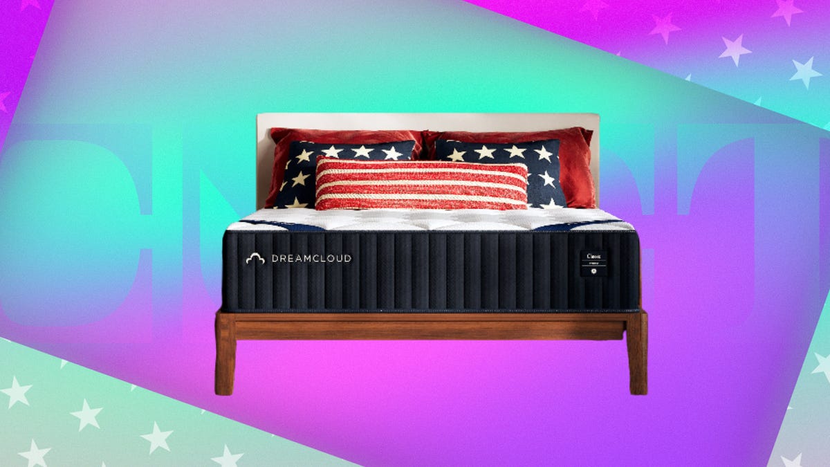 The DreamCloud Classic Hybrid mattress is displayed with patriotic flag-themed pillows against a mint and fuchsia background.