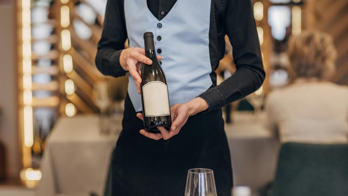 server holding bottle of wine