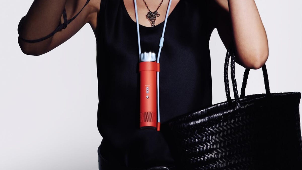 A red Dyson HushJet Mini Cool fan worn around a person's neck.