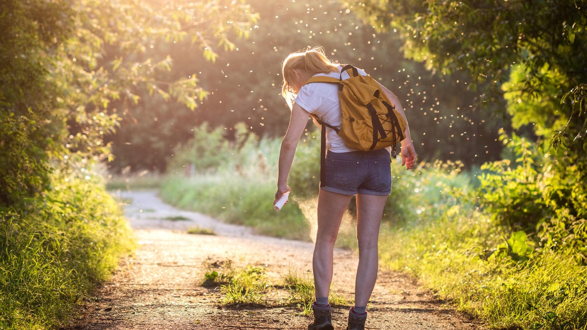 A woman sprays her legs with insect repellent