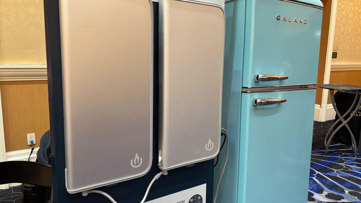 Two gray batteries with a blue refrigerator in the background.