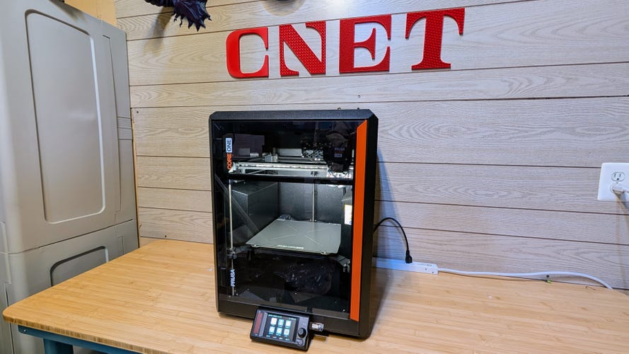The Prusa Core One on a wooden bench with the CNET logo behind