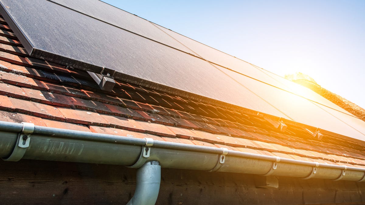 Dusty solar panels on a house with the sun beating down on them.