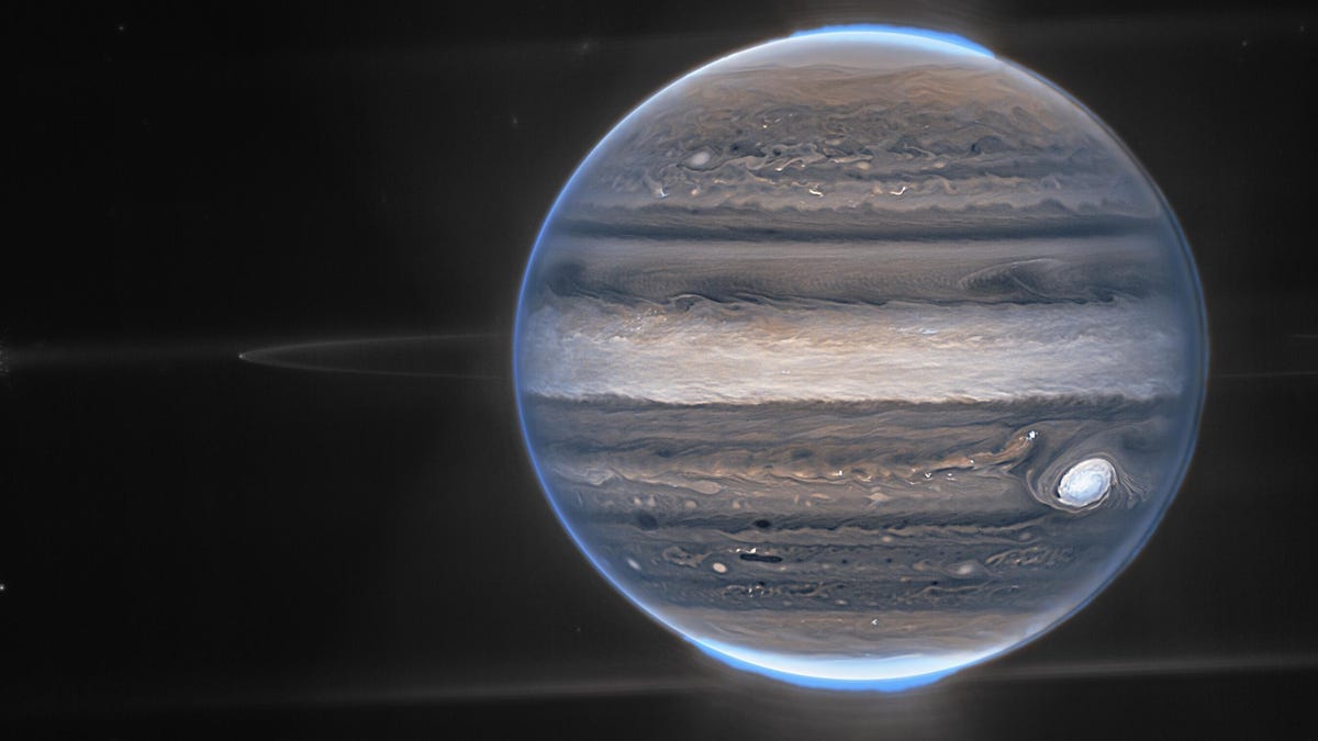 Jupiter in shades of blue and purple appears to glow in the upper reaches. Faint rings and moons are visible.