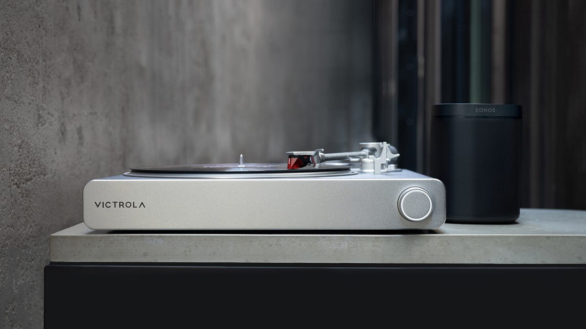 silver Victrola Stream Carbon turntable next to a black Sonos speaker